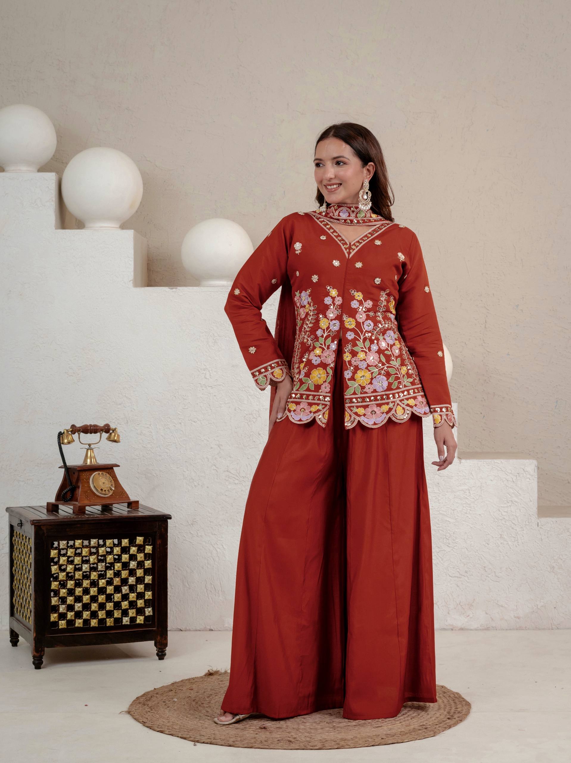 Resplendent Rust Orange Peplum Kurti and Flared Palazzo Suit Set Adorned with Intricate Multicolored Floral Embroidery, Sequin Accents, and Ornate Scalloped Borders